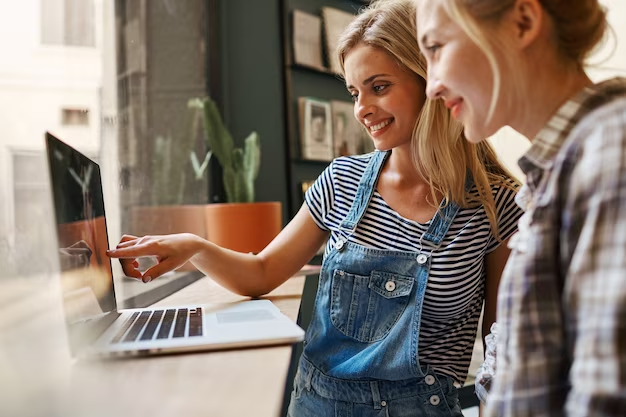 Two girls laughing and looking at laptop screen