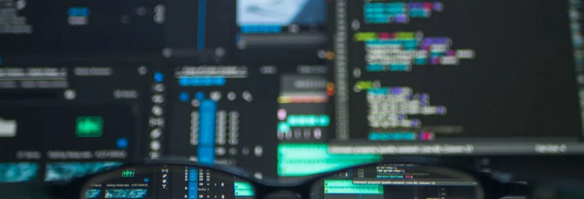 glasses and blurred background of a computer screen with coding on it